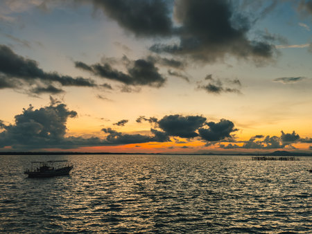 Colorful evening sky with boat floating on calm sea at sunsetの写真素材