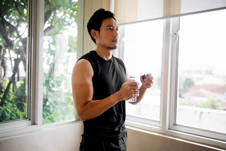 Male taking a moment after training session near natural light sourceの写真素材