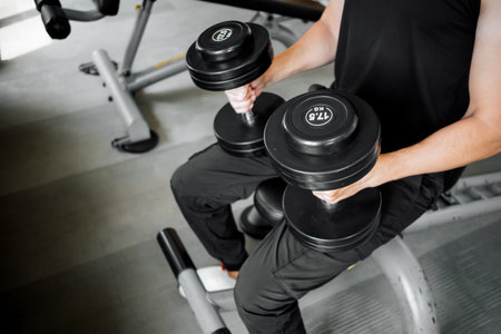 Male athlete preparing for exercise while holding heavy dumbbells in gymの写真素材