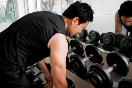Fit male selecting free weights before strength training sessionの写真素材