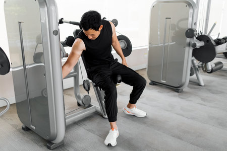 Tired fitness enthusiast taking a break after machine training sessionの写真素材