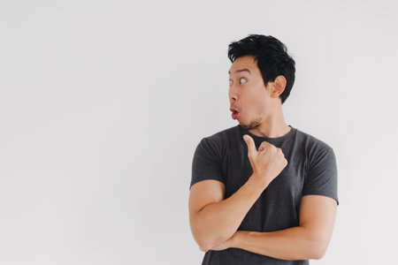 Thai male model turning head and pointing with questioning expression indoors