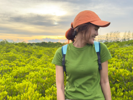 Young Asian female traveler admiring nature while wearing a green shirt and backpackの写真素材