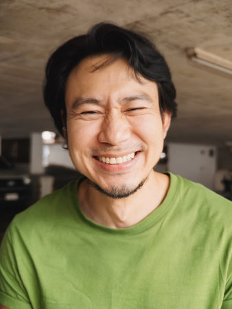 A cheerful man wearing a green shirt beams a bright smile, radiating positivity and warmth all around himの写真素材