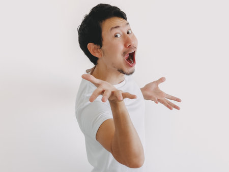 Thai male turning sideways with open hands and panicked facial expression, reacting with fear and tension, Asian ethnicityの写真素材