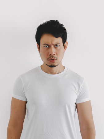 Thai male with short black hair and average build looking serious while standing against white background, Asian ethnicityの写真素材