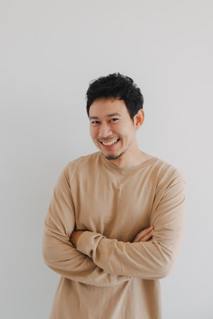 Young Asian male stands with composed posture and warm smile indoors