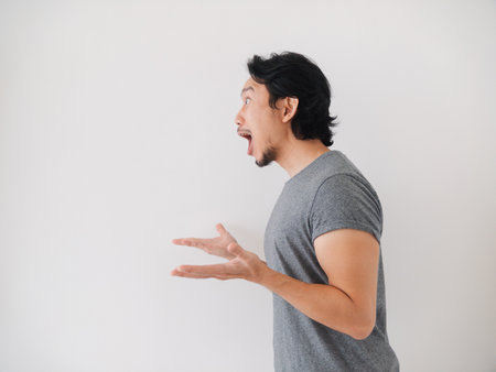 Happy and surprise reaction of Asian man in grey t-shirt isolated on white. High quality photoの写真素材