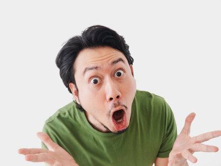 Surprised and shocked face Asian man in green t-shirt isolated on white. High quality photoの写真素材