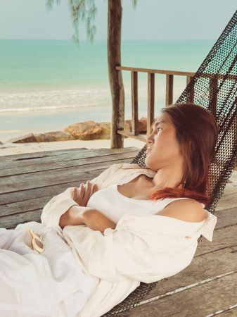 Beach relaxed vibe of Asian woman sleeping on hammock by the beach in Asia.の写真素材
