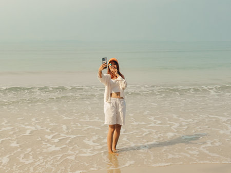 Happy Asian woman enjoy taking selfie photo on the beach in Thailand.の写真素材