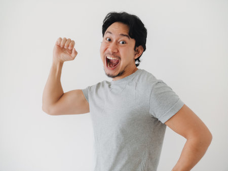 A cheerful young man is expressing his excitement and success through a triumphant and victorious pose of joyの写真素材