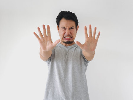 Man with a beard and a shirt on is making a hand gesture that looks like he is saying no
