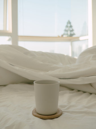 Morning coffee on rumpled white bed, ceramic mug on cork coaster, soft sunlight filtering through...