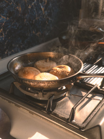 Close action shot of hand using tongs to flip buns in skillet, kitchen hustle, practical cookwork choreography, morning prep