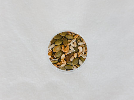 Pumpkin seeds in a glass on a white background, top view