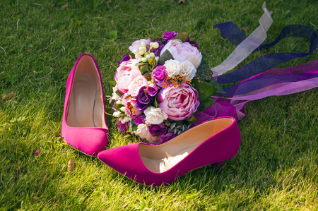 A wedding bouquet with the bride's pink shoes on the grassの写真素材
