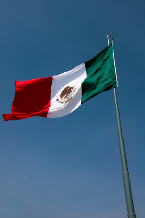 Mexican flag waving in the wind on blue sky background, Mexico