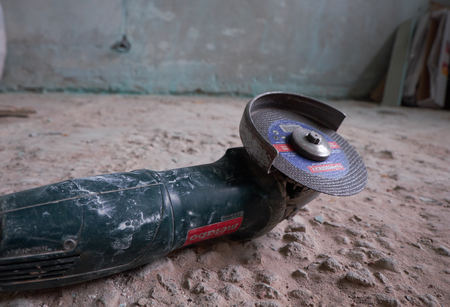 Side grinder on a floor in front of a dirty wall. Overhaul conceptのeditorial素材