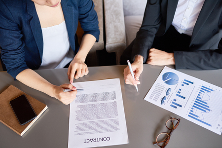 Top view of business table with contract document and unrecognizable people working at it making successful financial dealの写真素材