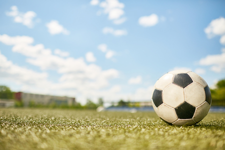 Closeup of ball lying on green grass in empty football field, copy spaceの写真素材