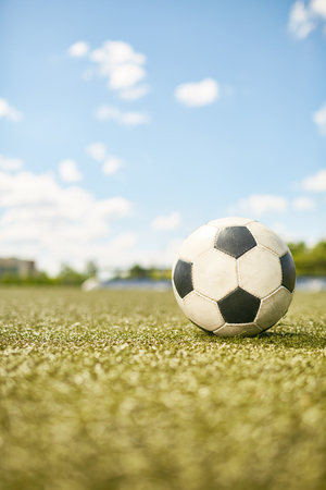 Closeup of ball lying on green grass in empty football field in sunlightの写真素材