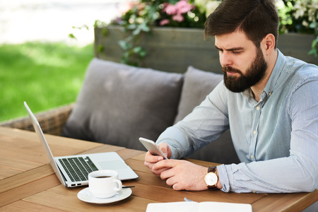 Bearded Businessman using Smartphone in Cafe Outdoorsの写真素材
