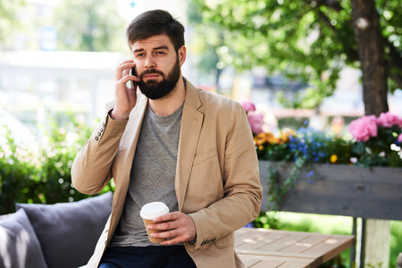Contemporary Man Speaking by Phone in Cafe Outdoorsの写真素材