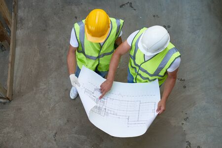 Top View of Builders Holding Blueprintsの写真素材
