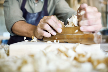 Close-up shot of unrecognizable craftsman using jointer plane, shavings on foreground