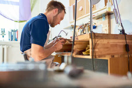 Portrait of young man working at table  in workshop with wood or metalの写真素材