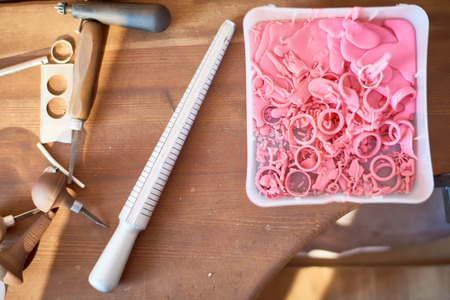 Above view of jewelers tools, ring size measurer next to shreds of used forms