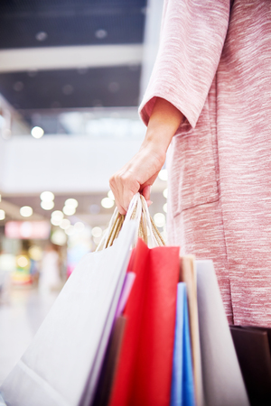 Closeup of young woman holding paper bags with purchases while shopping in mallの写真素材