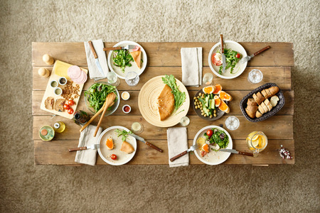 Above view of wooden dinner table with half-eaten dishes left on it, no peopleの写真素材