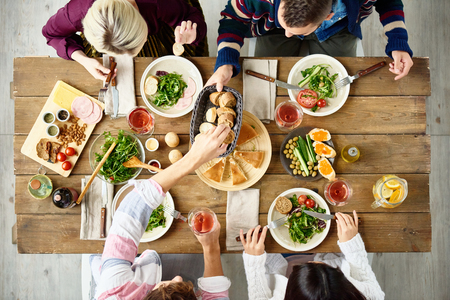 Above view of four people eating delicious food at festive dinner table in cafeの写真素材