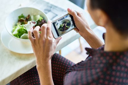 Young Woman Taking Photo of Salad in Cafeの写真素材