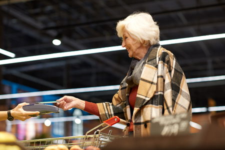 Senior Woman Using NFS in Supermarketの写真素材
