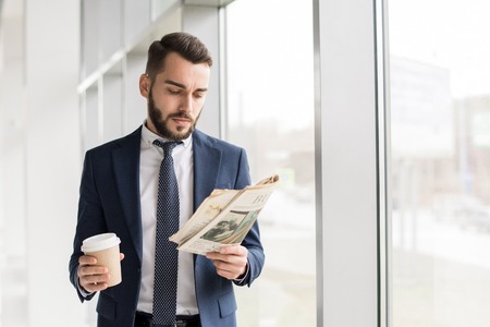 Handsome Businessman Reading Newspaper by Windowの写真素材
