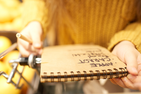 Close up of unrecognizable little girl holding shopping list while buying groceries in supermarketの写真素材