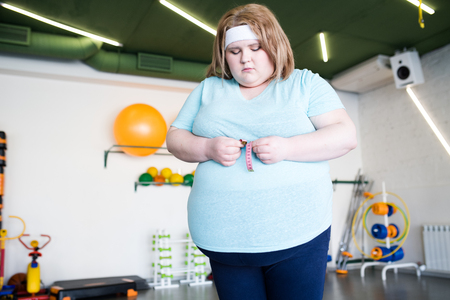 Sad Obese Woman Measuring Waistの写真素材