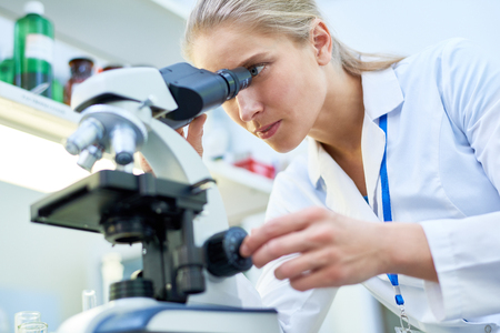 Skilled scientist viewing biological substance through microscopの写真素材