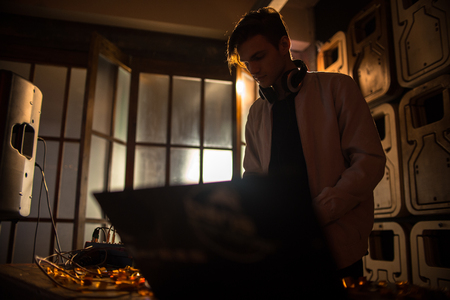 Young DJ Playing in Dark Club