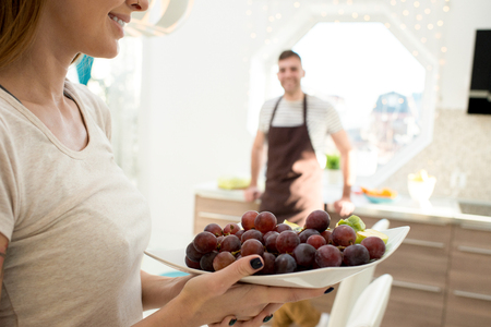 Smiling woman carrying bowl with grapesの写真素材