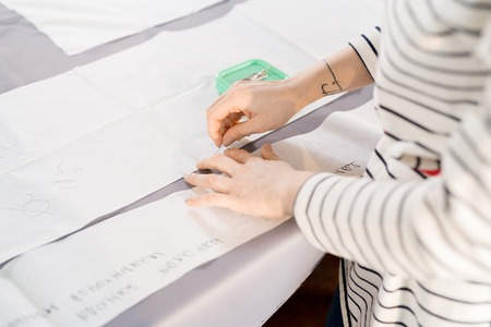 Close up of unrecognizable female tailor tracing fabric with white chalk while sewing custom made clothes, copy spaceの写真素材