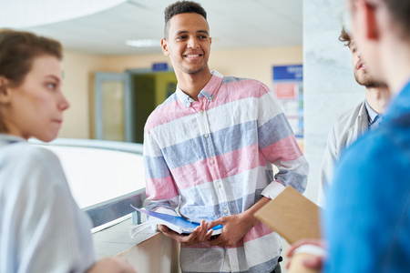 Smiling handsome student talking to groupmatesの写真素材