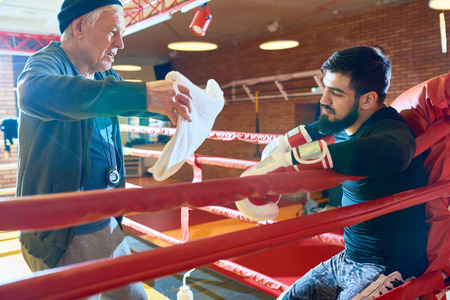 Boxer taking rest on ring with coachの写真素材