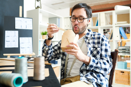 Chilling designer enjoying takeaway foodの写真素材