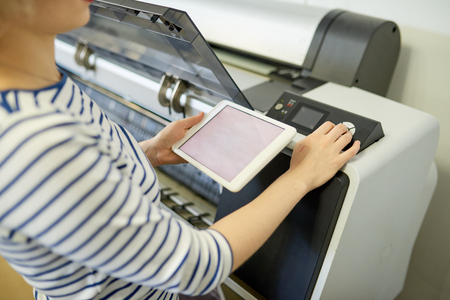 Faceless woman setting printer with tablet
