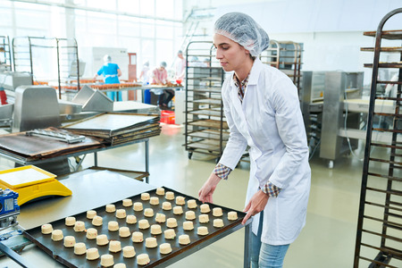 Confectioner holdingÂ baking sheet with raw pastryの写真素材