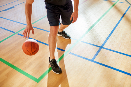 Crop man dribbling basketball ballの写真素材